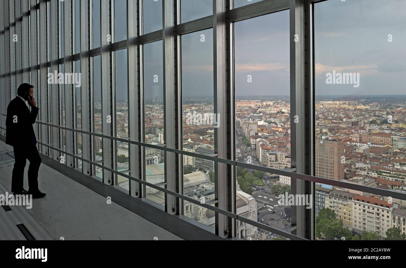 Businessman facing a top window city view, from the historical Pirelli skyscraper, in Milan. Stock Photo