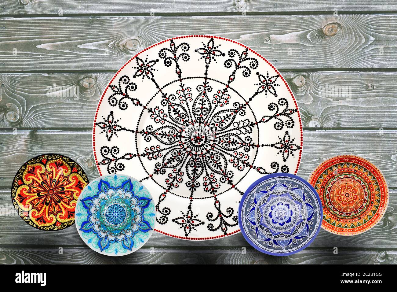 Set of decorative ceramic plates hand painted dot pattern with acrylic paints on a gray wooden background. Copy space. Stock Photo