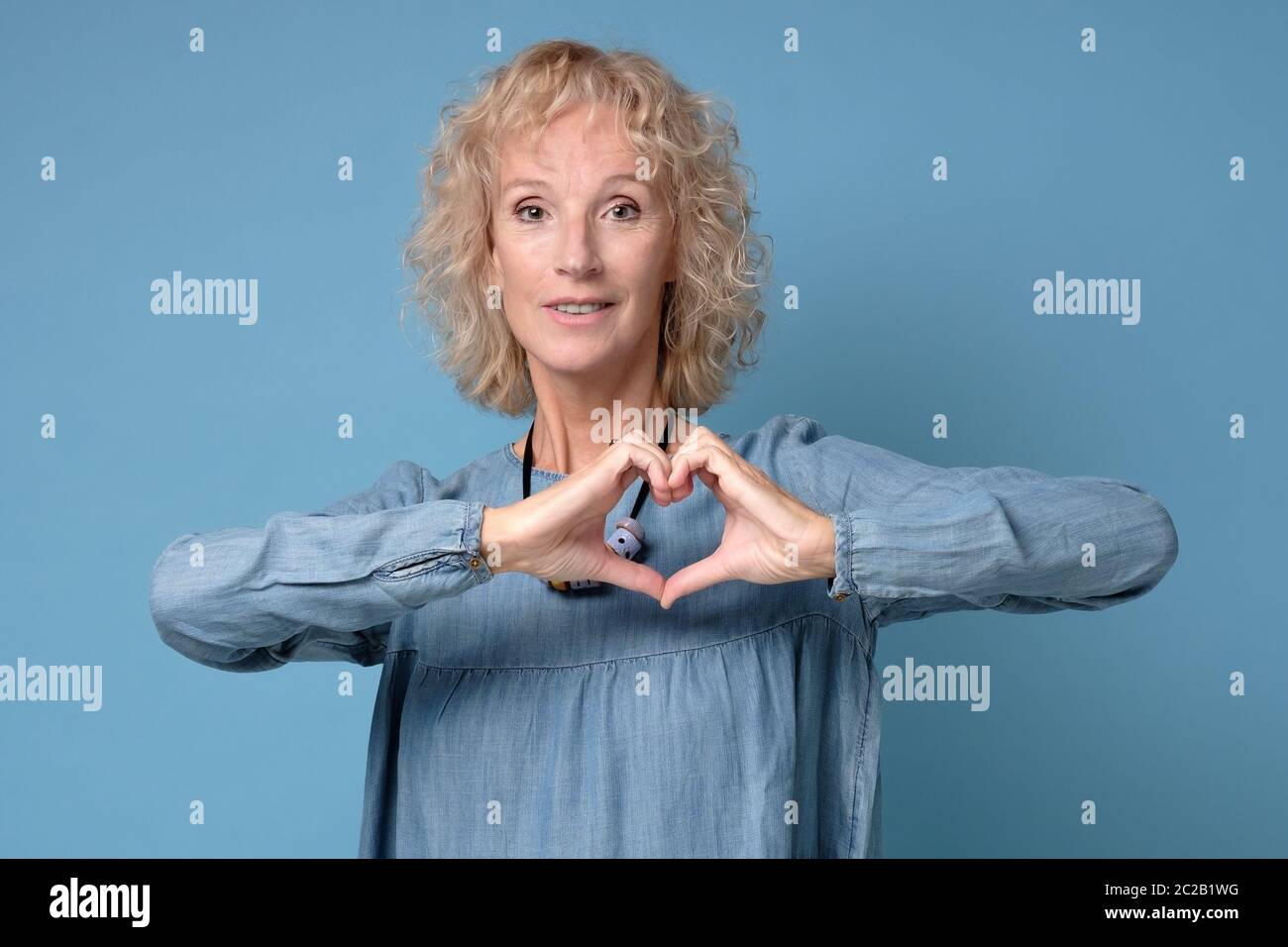 Mature caucasian womna making a heart symbol with her hands Stock Photo