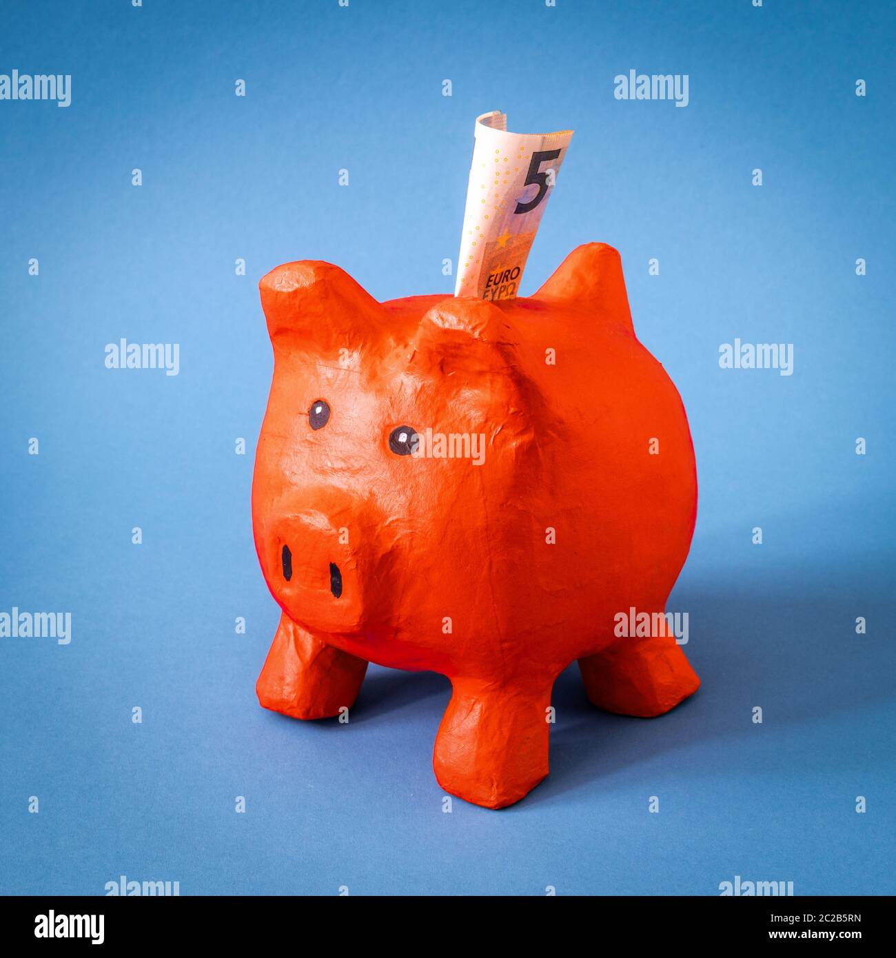 red papier mache piggy bank with 5 Euros Stock Photo