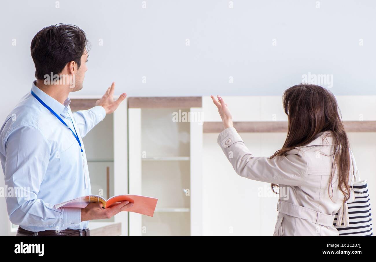 Salesman explaining to woman customer at furniture store Stock Photo ...