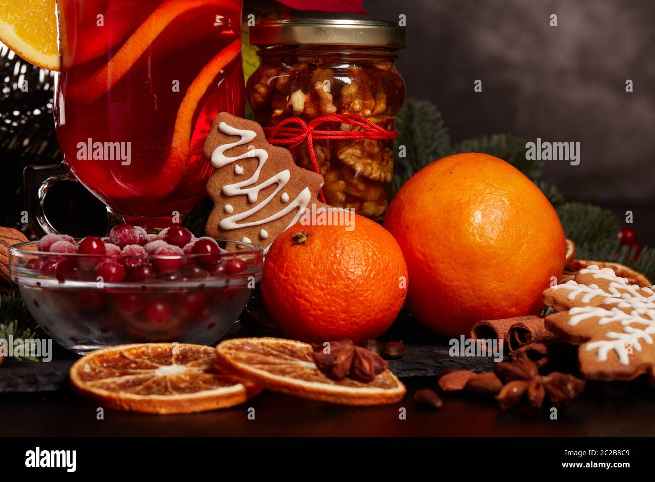 Still life with glasses of mulled wine or fruit tea, Red Poinsettia flowers, fir branch and spices on a dark background. New year and Christmas table Stock Photo