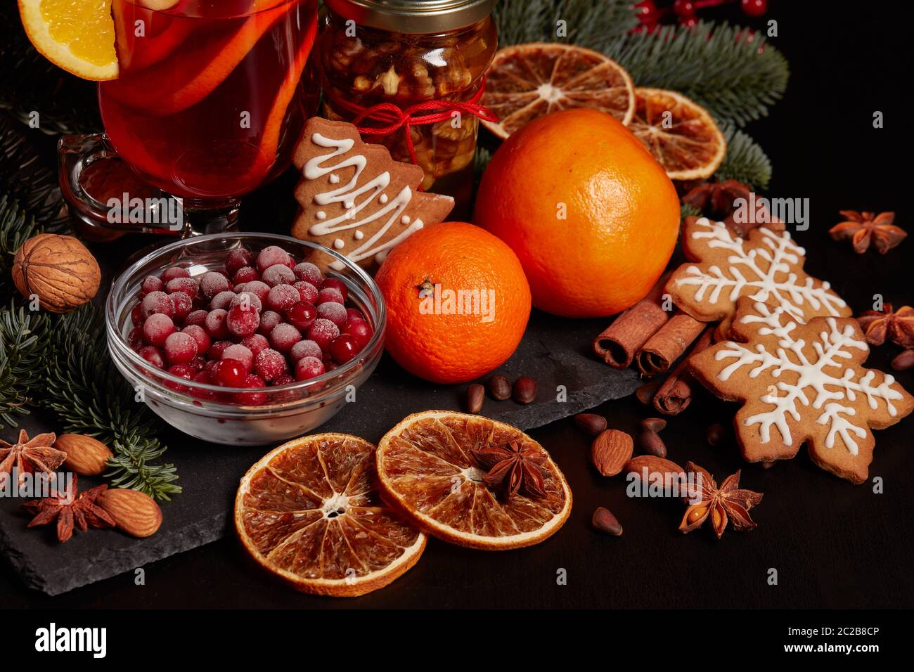 Still life with glasses of mulled wine or fruit tea, Red Poinsettia flowers, fir branch and spices on a dark background. New year and Christmas table Stock Photo