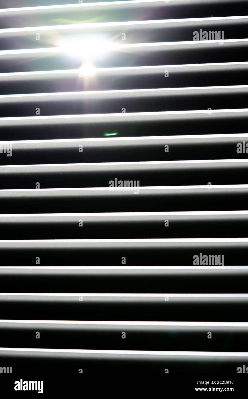 Thin lines of light on the wall. Shadow from the blinds. bathroom. Stock Photo