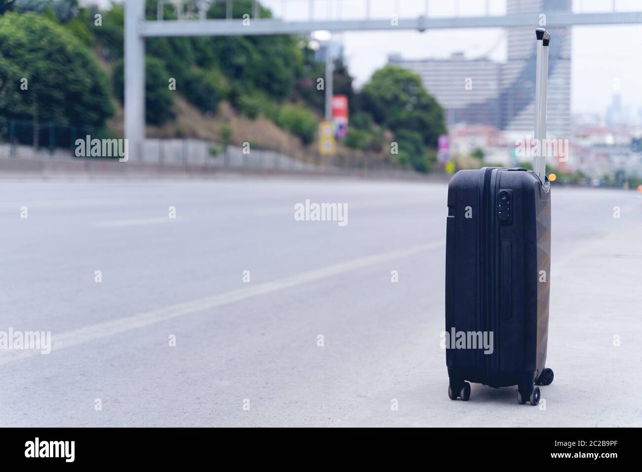Modern suitcase on a asphalt road. Stock Photo