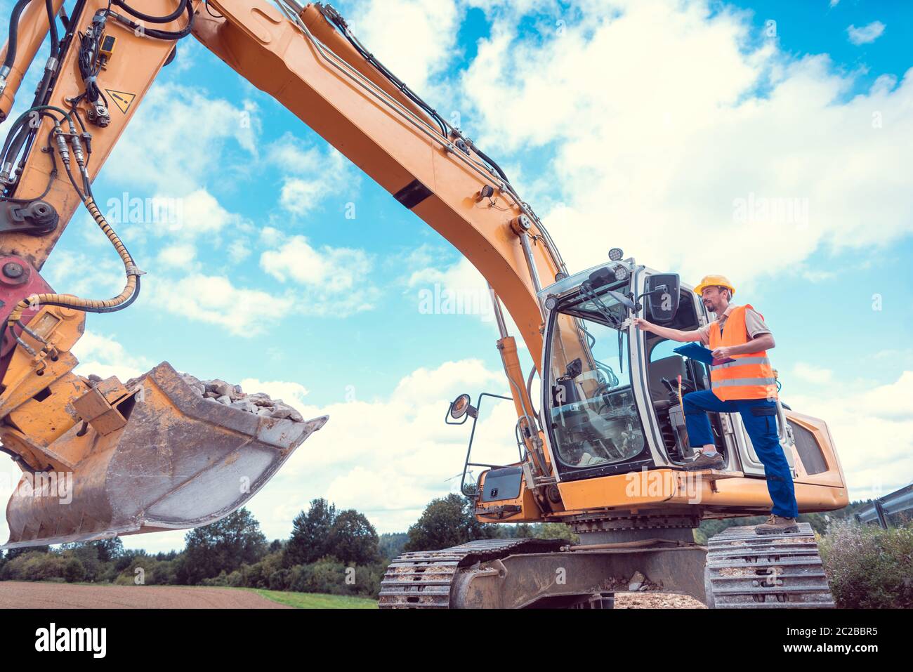 Construction worker on excavator planning the work to be done on the site Stock Photo