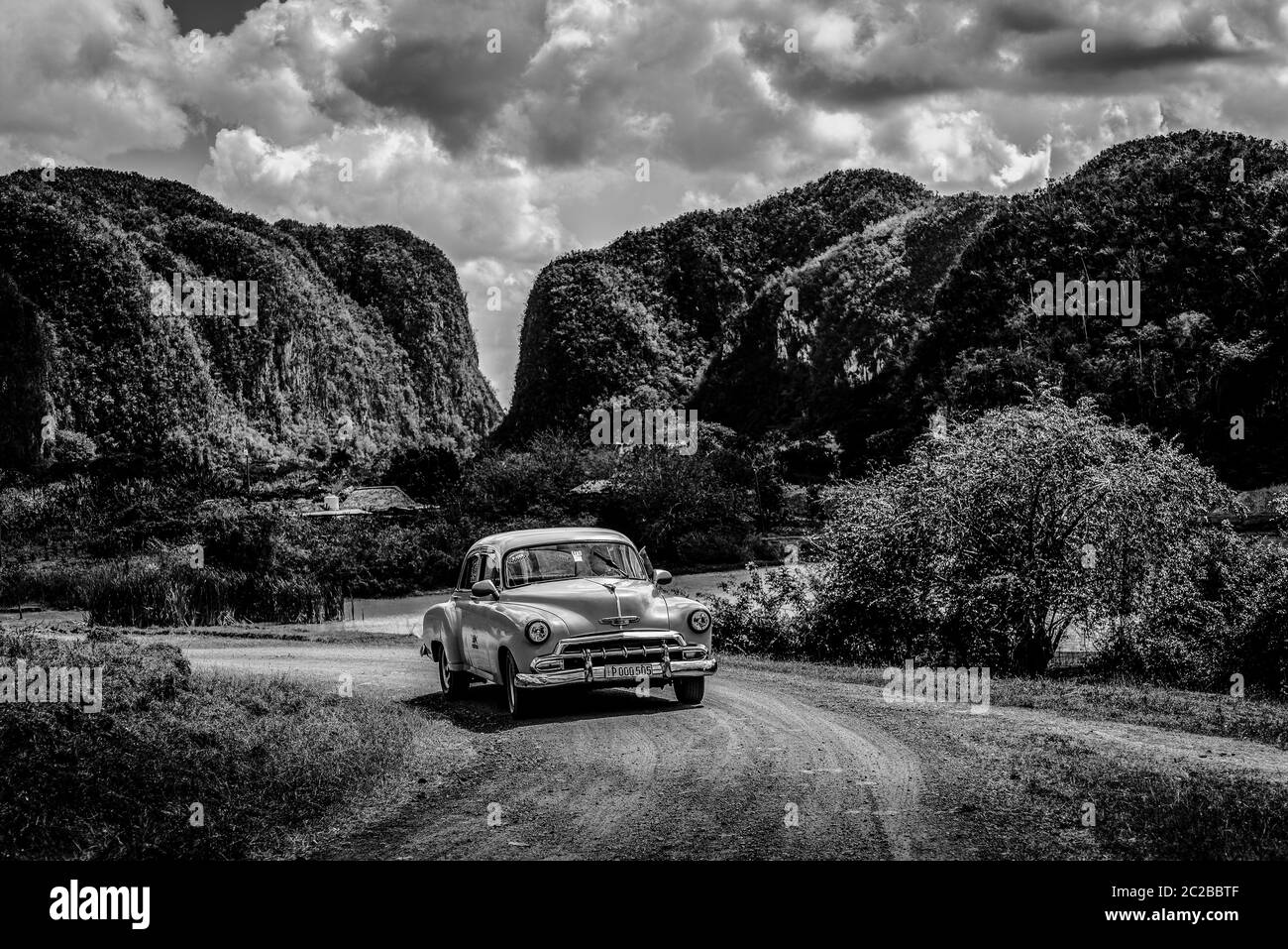 Classic car driving on dirt road in Vinales Valley, Cuba Stock Photo