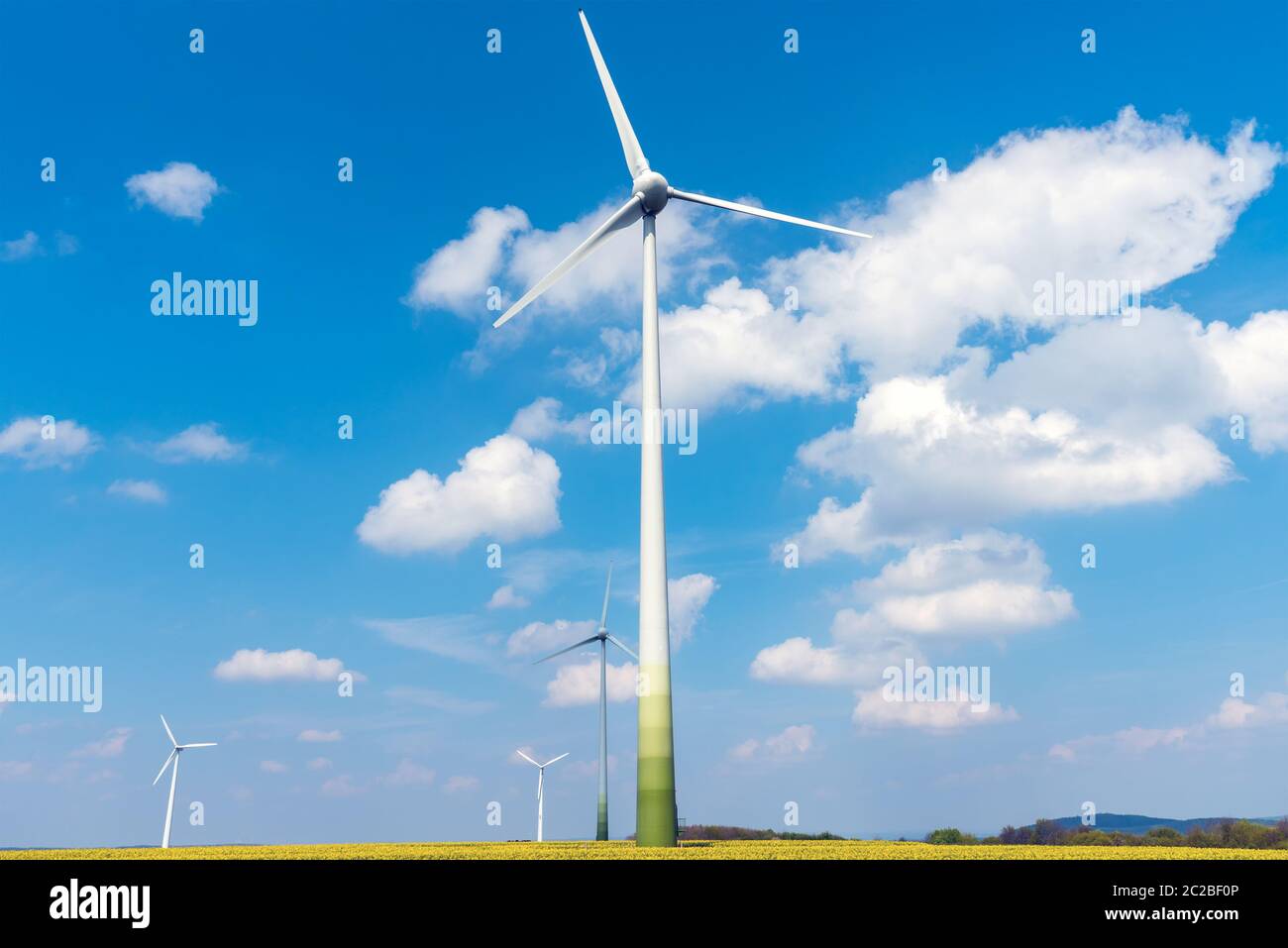 Wind turbines and flowering oilseed rape seen in Germany Stock Photo