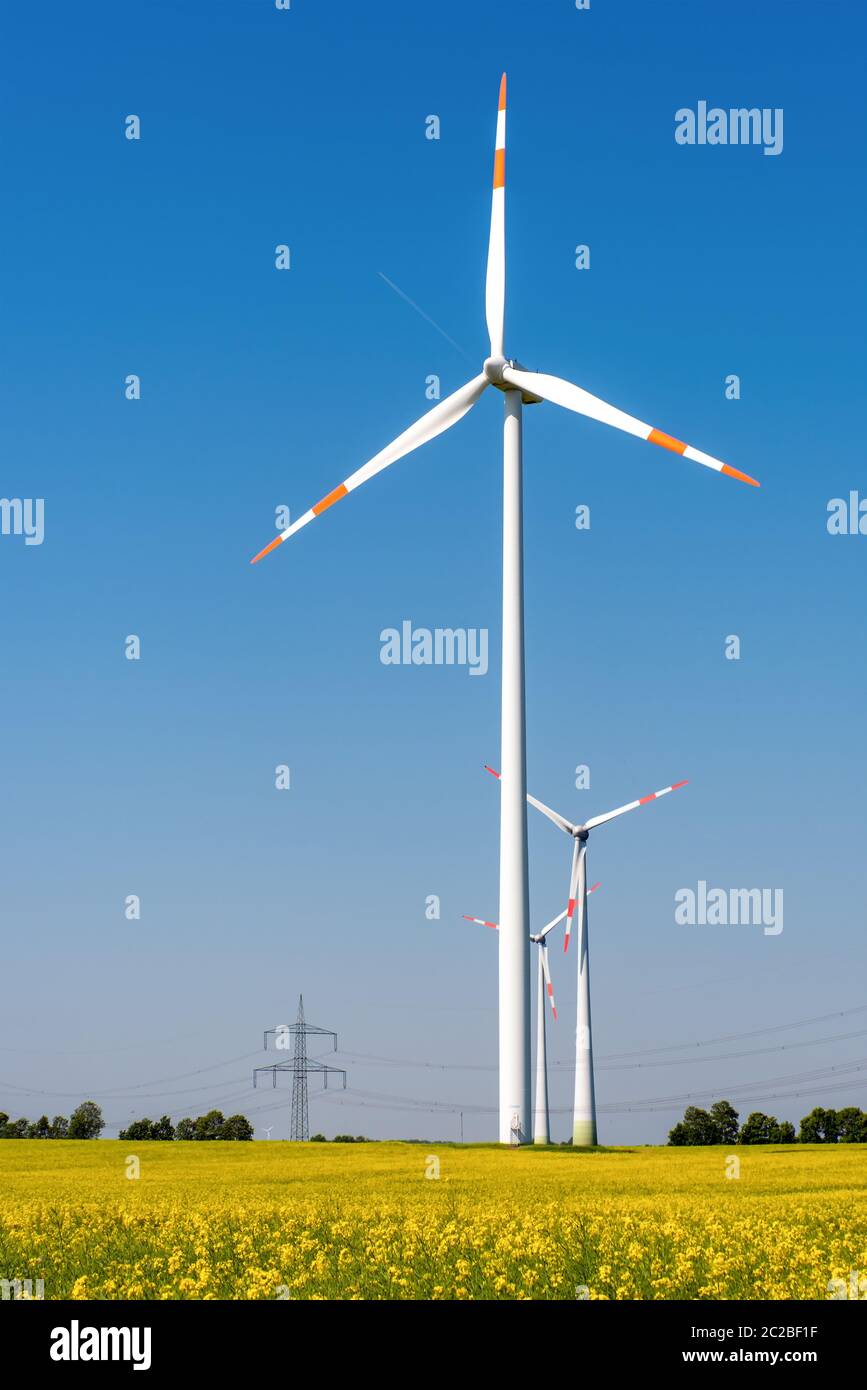 Wind turbines, power lines and flowering rapeseed seen in Germany Stock Photo