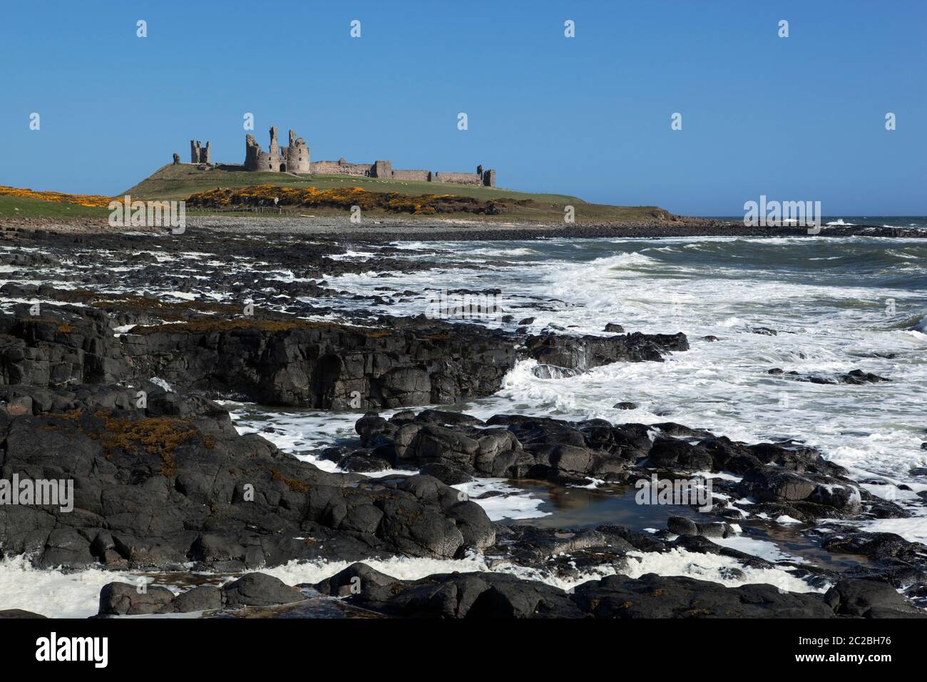 Rough seas below ruins of medieval Dunstanburgh Castle, Alnwick, Northumberland, England, United Kingdom, Europe Stock Photo