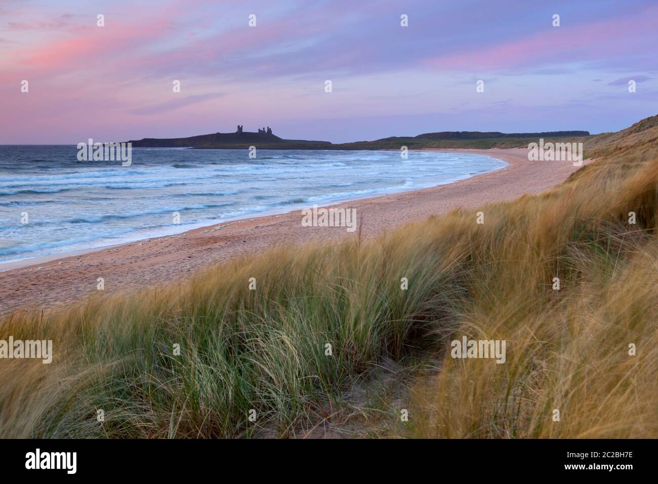 Sunrise over Embleton Bay and the ruins of medieval Dunstanburgh Castle, Alnwick, Northumberland, England, United Kingdom, Europe Stock Photo