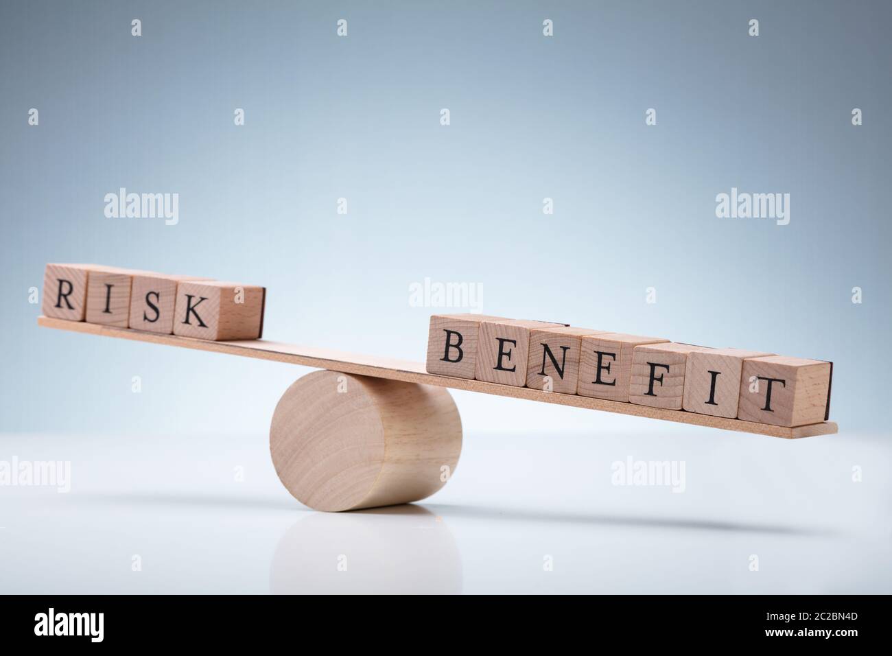 Close-up Of Risk And Benefit Wooden Blocks On Seesaw Against Reflective ...