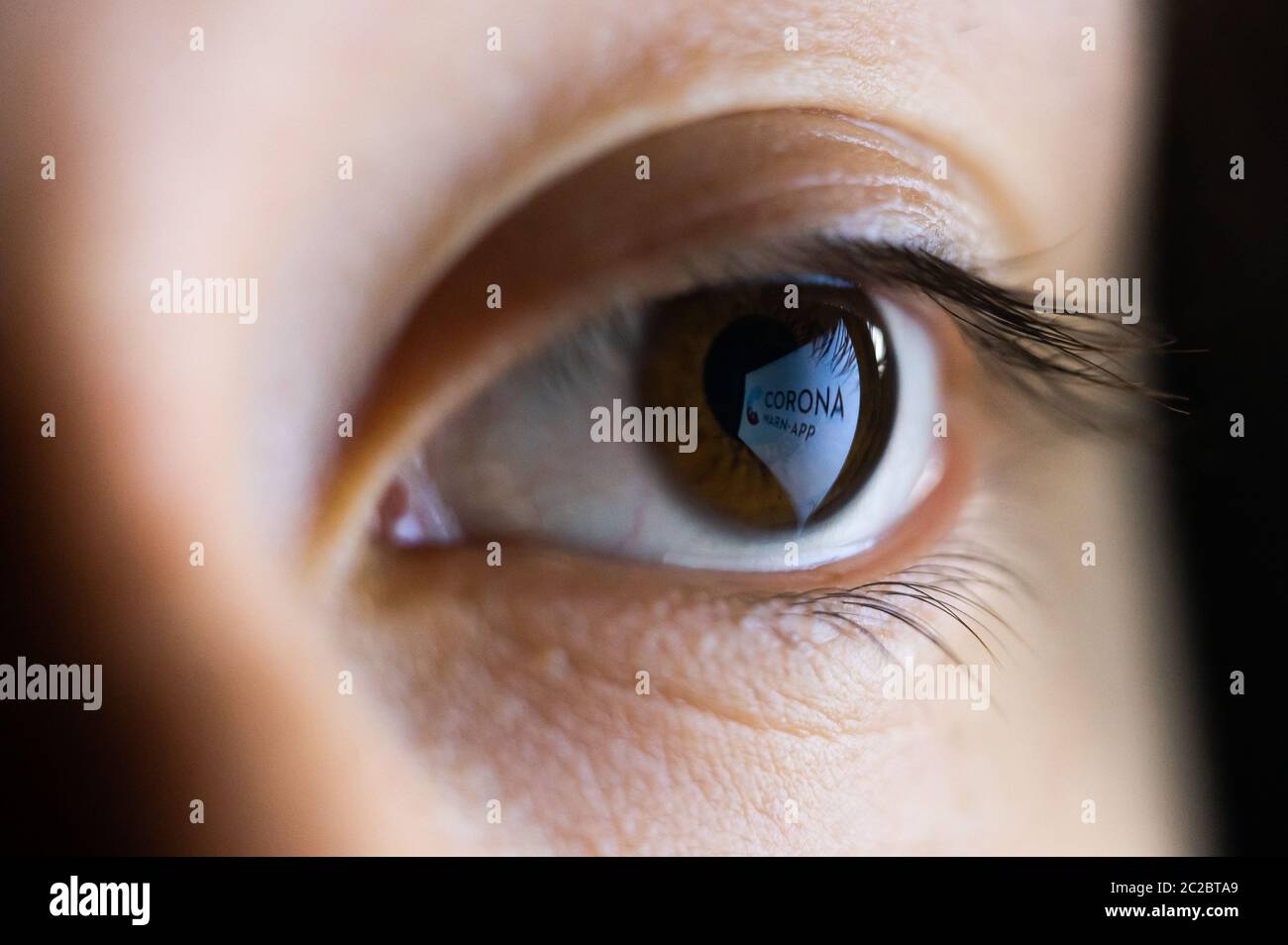 Villingen Schwenningen, Germany. 16th June, 2020. ILLUSTRATION - A woman's eye reflects the logo of the Corona warning app from a smartphone. The app is intended to enable contact tracing of infected persons and thus shorten the infection chains. Credit: Silas Stein/dpa/Alamy Live News Stock Photo