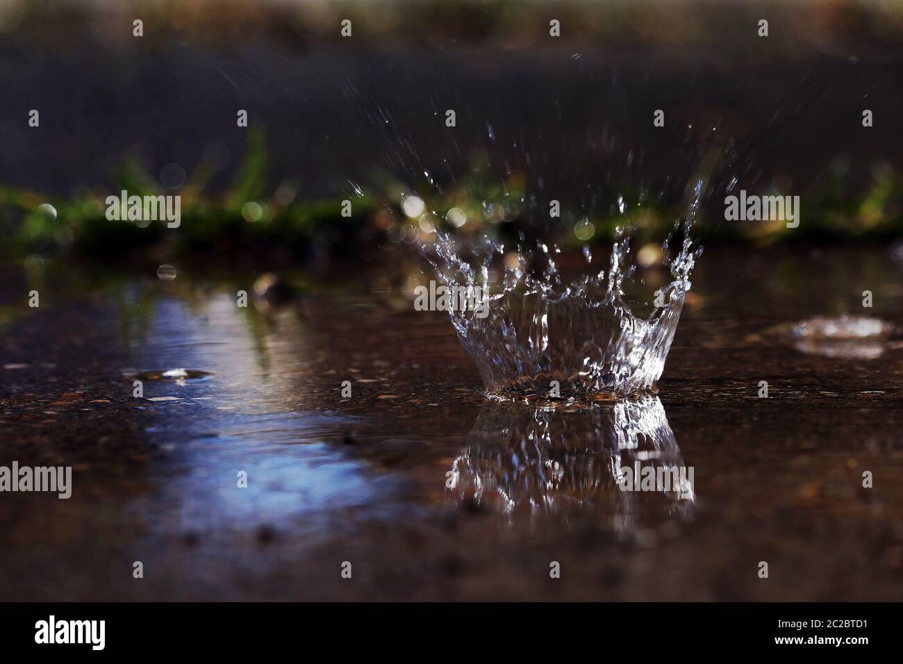 A large drop of rain hits the ground Stock Photo