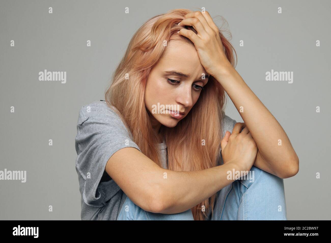 Crying young woman with feels unhappy and depressed, looking down and touching her forehead. Problem in relationships, relationships breakup, love dep Stock Photo