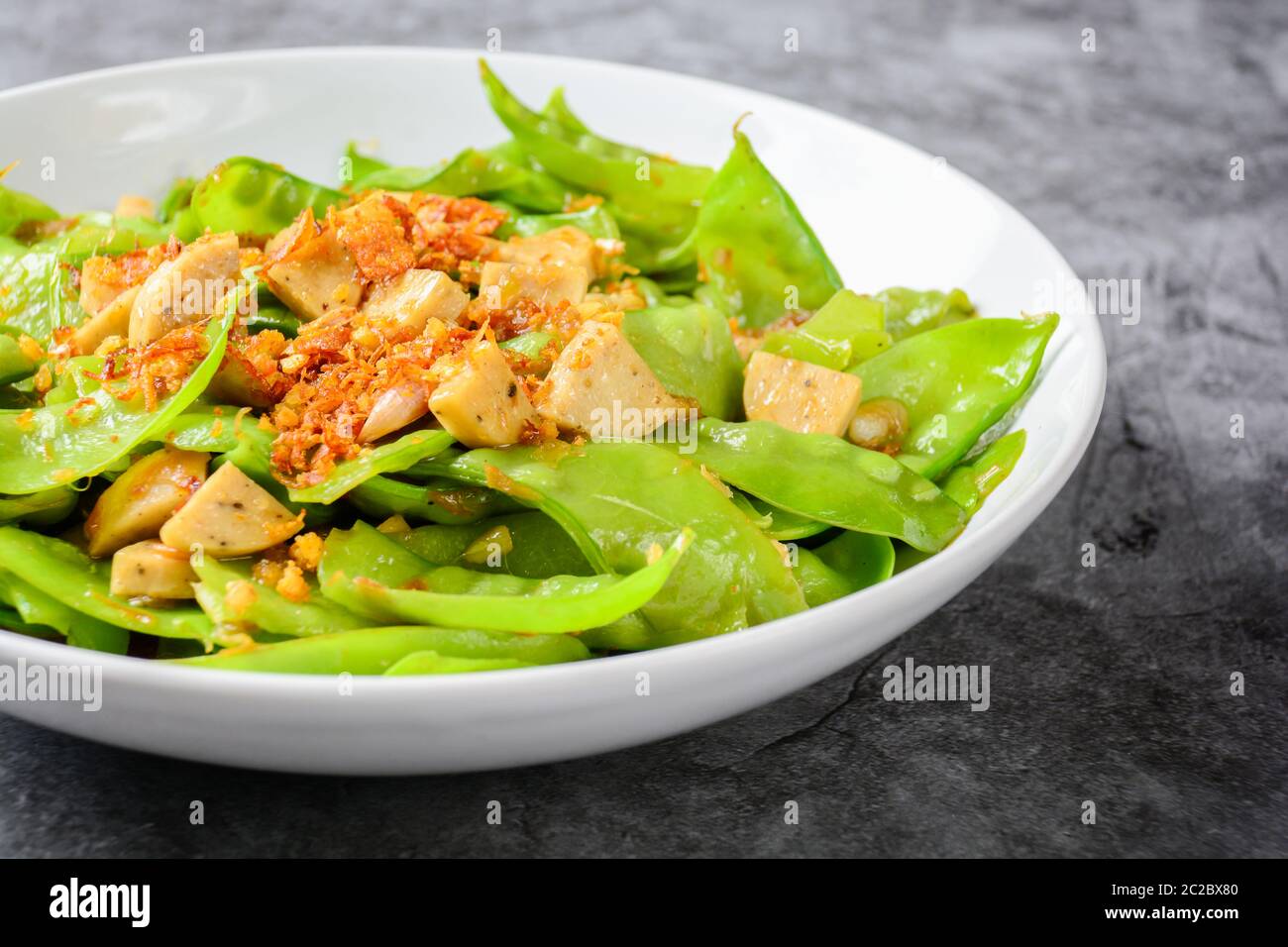 Stir Fry Snow Peas with Vietnamese Grilled Pork Sausage, topping with crispy fried shallots and garl Stock Photo