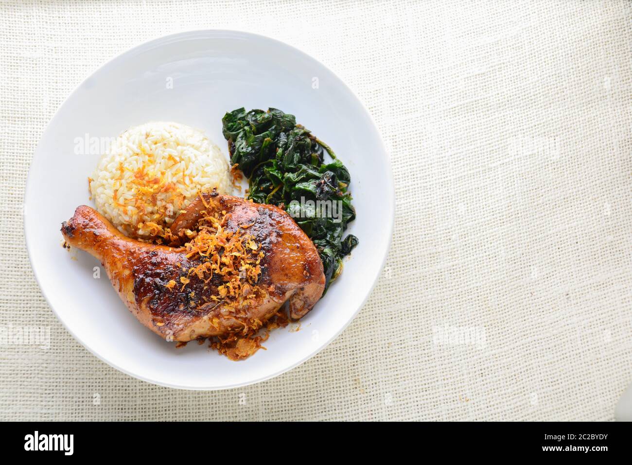 Chicken drumstick marinated with spicy chilli sauce and herbs, served with cooked rice and spinash. Stock Photo