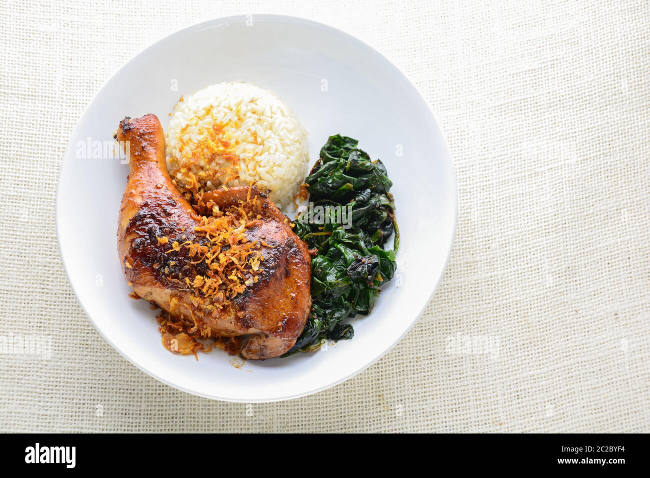 Chicken drumstick marinated with spicy chilli sauce and herbs, served with cooked rice and spinash. Stock Photo