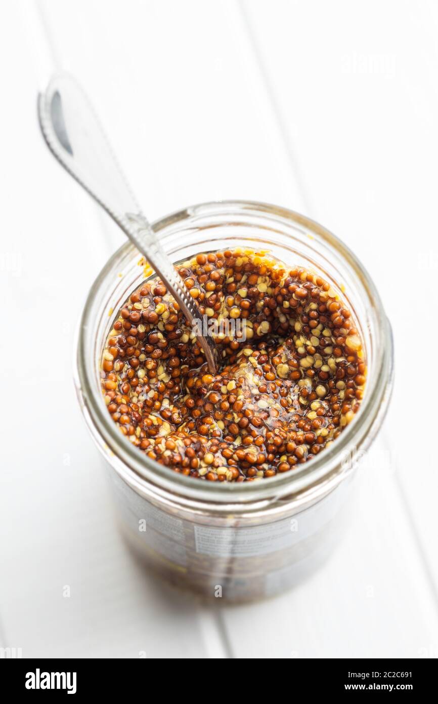 Whole grain mustard in jar on white table Stock Photo Alamy
