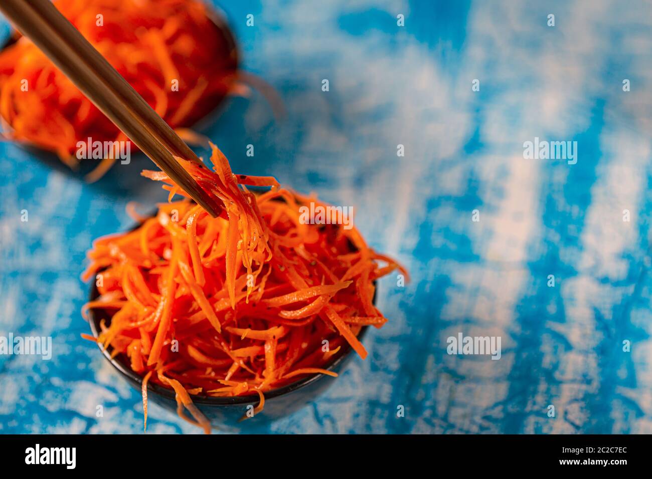 Korean carrot pickled salad on blue background. Fresh carrot on the