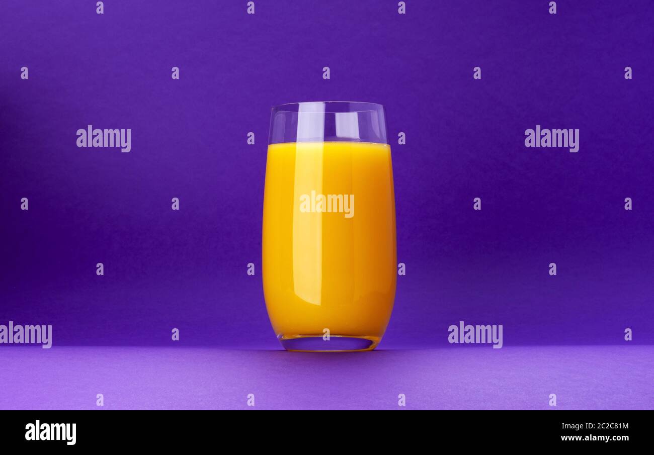 Glass of orange juice isolated on violet background with copy space Stock Photo