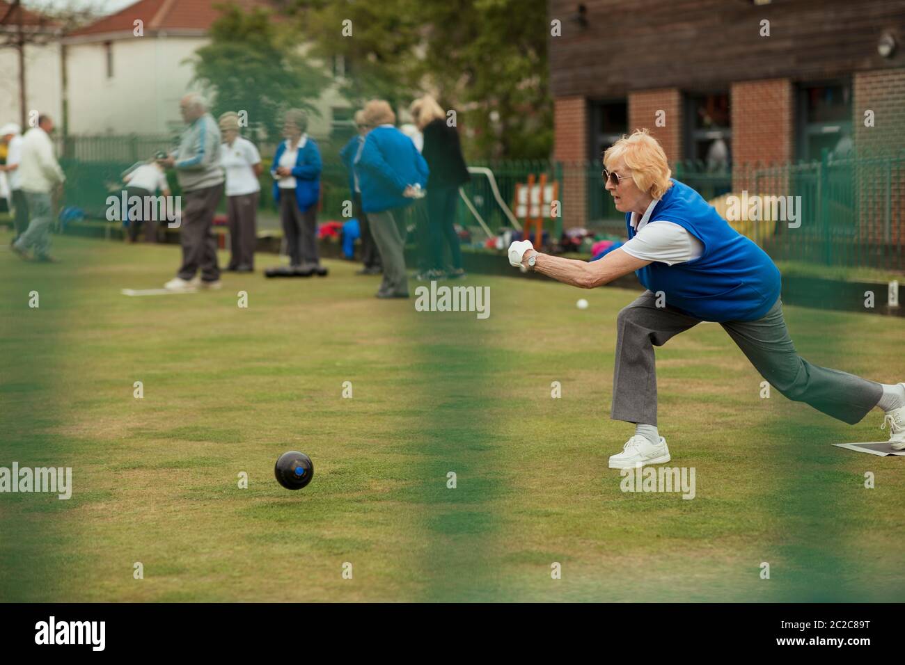 A side view shot of a senior woman taking her shot in a game of lawn bowling. Stock Photo