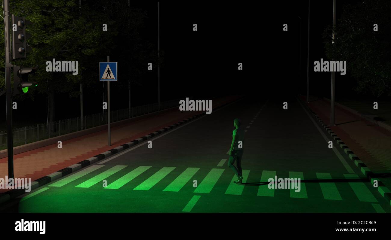 A pedestrian crosses the road on an unlit street at night at the green