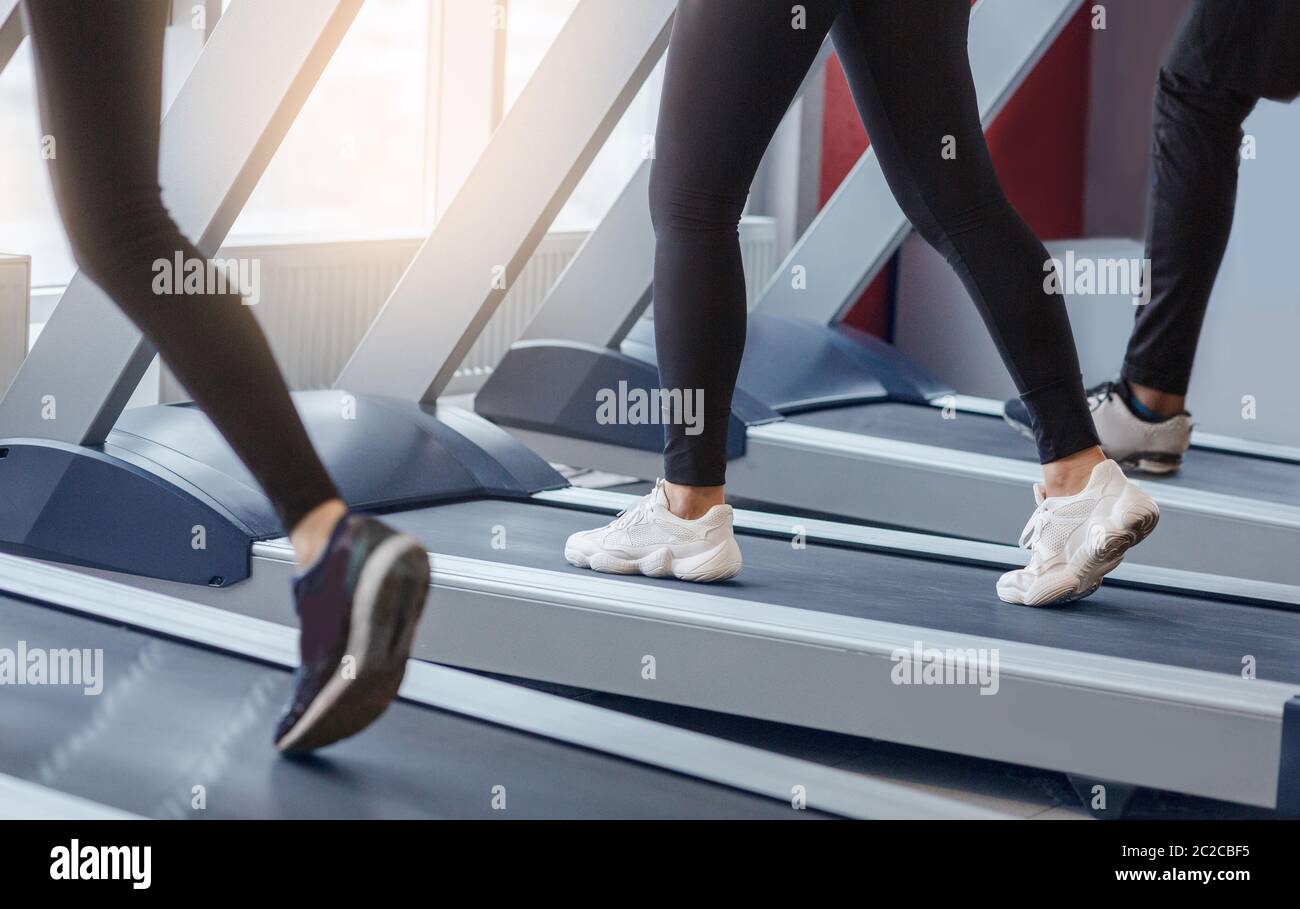 Sporty people on running machines at fitness centre, close up of legs Stock Photo