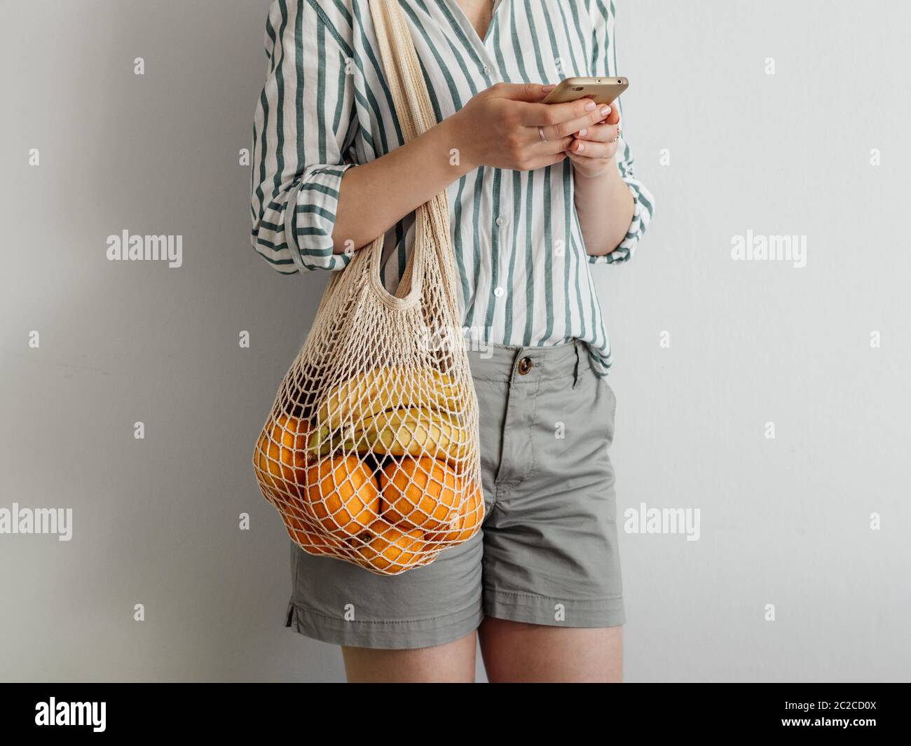 woman with mesh bag on shoulder using smartphone Stock Photo