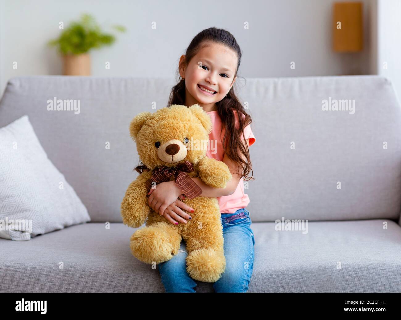 Chinese Girl Hugging Teddy Bear Sitting On Couch At Home Stock Photo ...