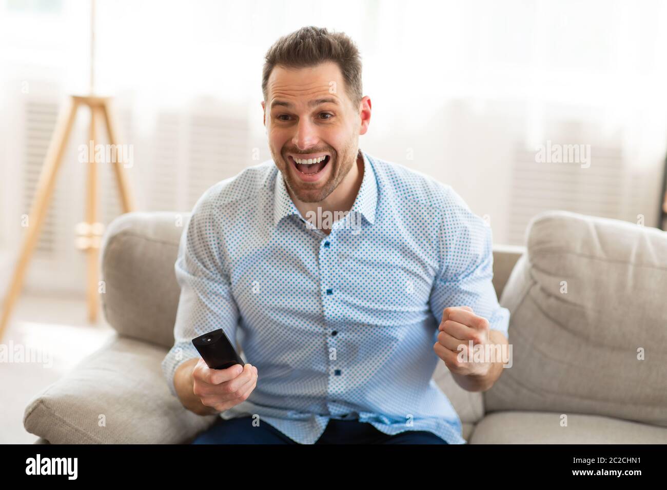 Emotional handsome man watching football game at home Stock Photo