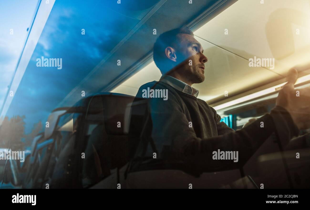 Caucasian Men and His Business Travel in Coach Bus. Public Transportation Theme. Passenger Behind Bus Window Talking to Someone. Stock Photo