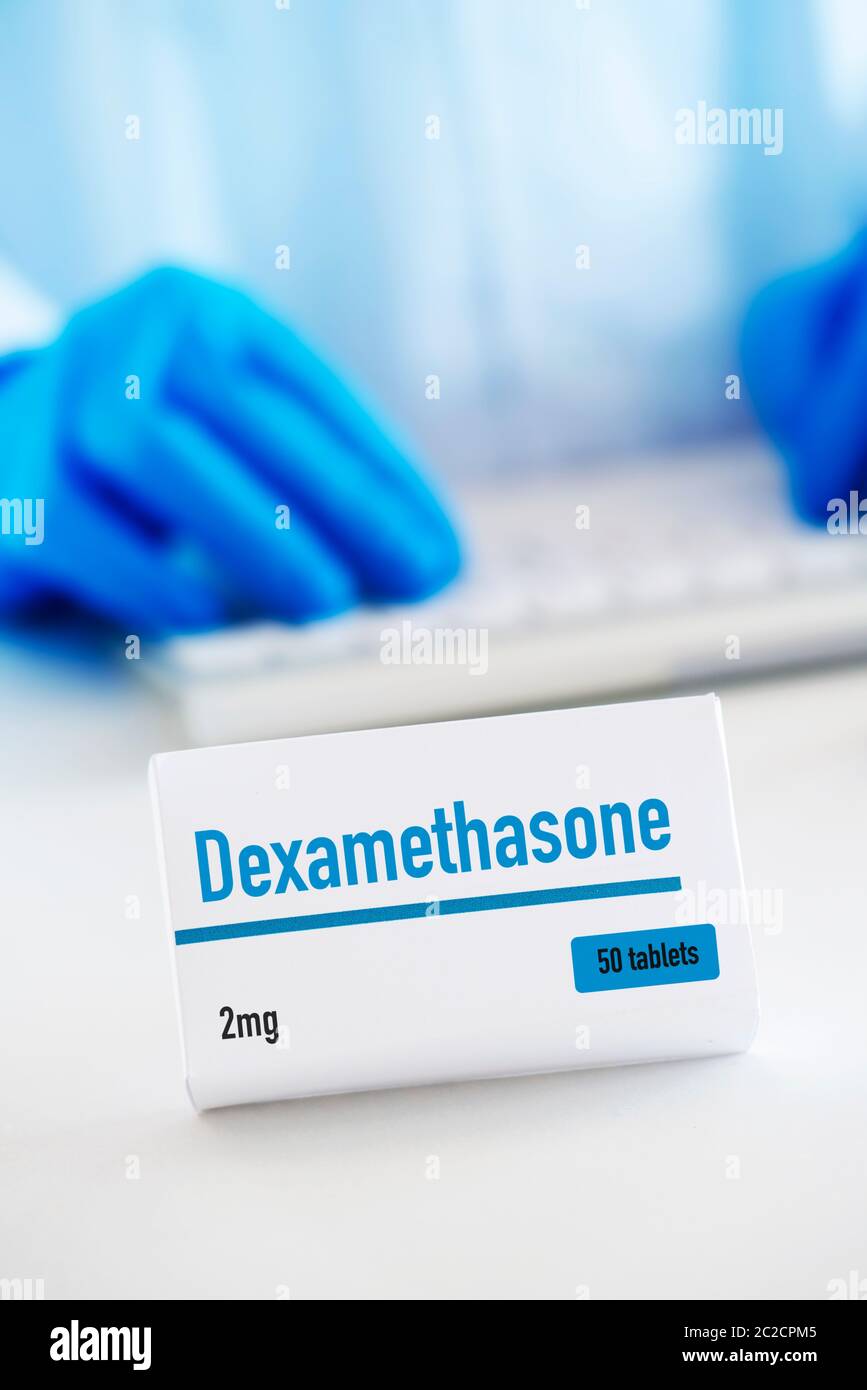 closeup of a simulated box of dexamethasone on a white table, and a man of a man wearing a white coat and blue surgical gloves in the background Stock Photo