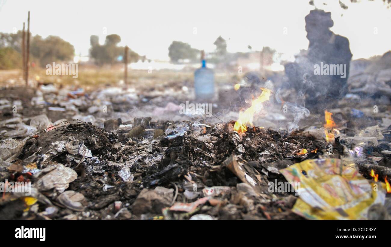 Burning trash and poor Indian old man. Stock Photo