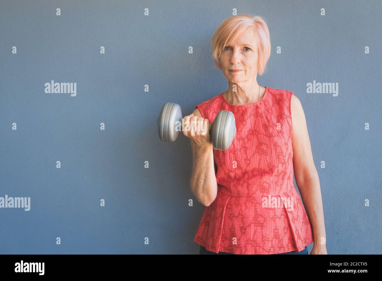 Mature woman keeping fit by lifting weights at home Stock Photo