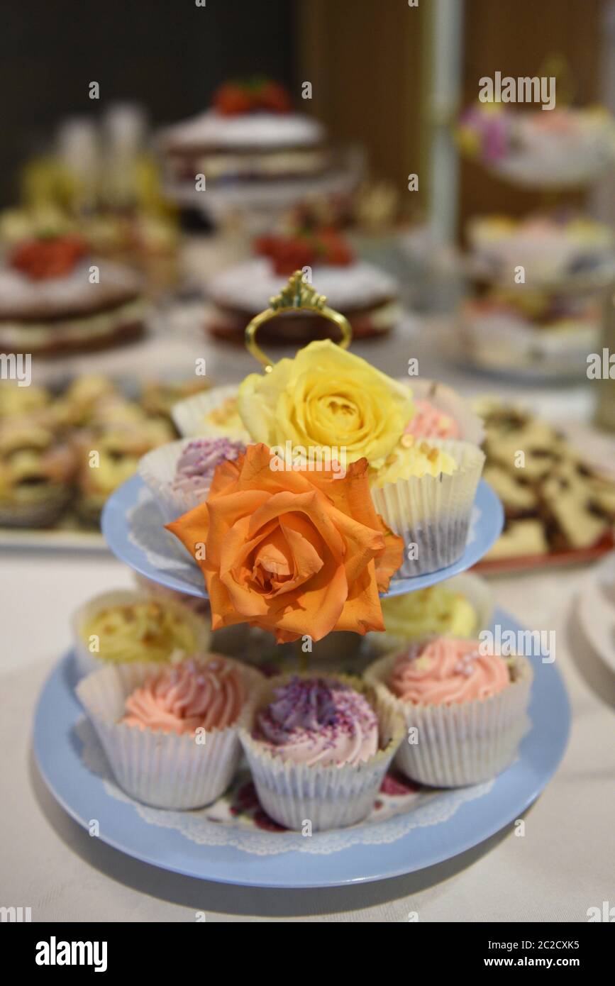 Fancy cakes on a cake stand at a buffet. Selective focus. Real life selection of tea and fairy cakes at a party celebration. Stock Photo