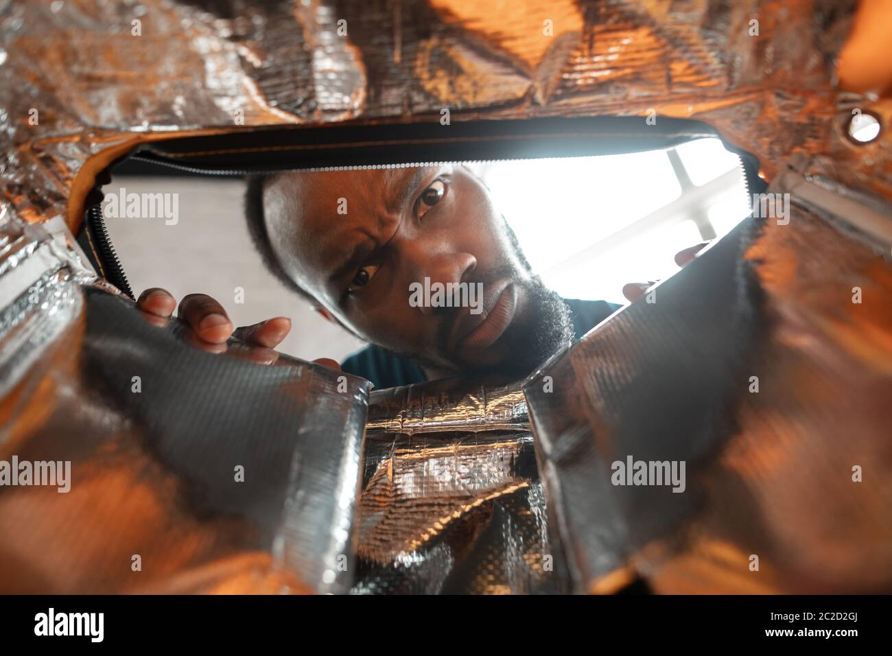 In old postal, delivery box. African-american man looking for job in unusual places at his home. Crazy, funny way to find career and going up. Concept of crisis, unemployment, finance, business. Stock Photo