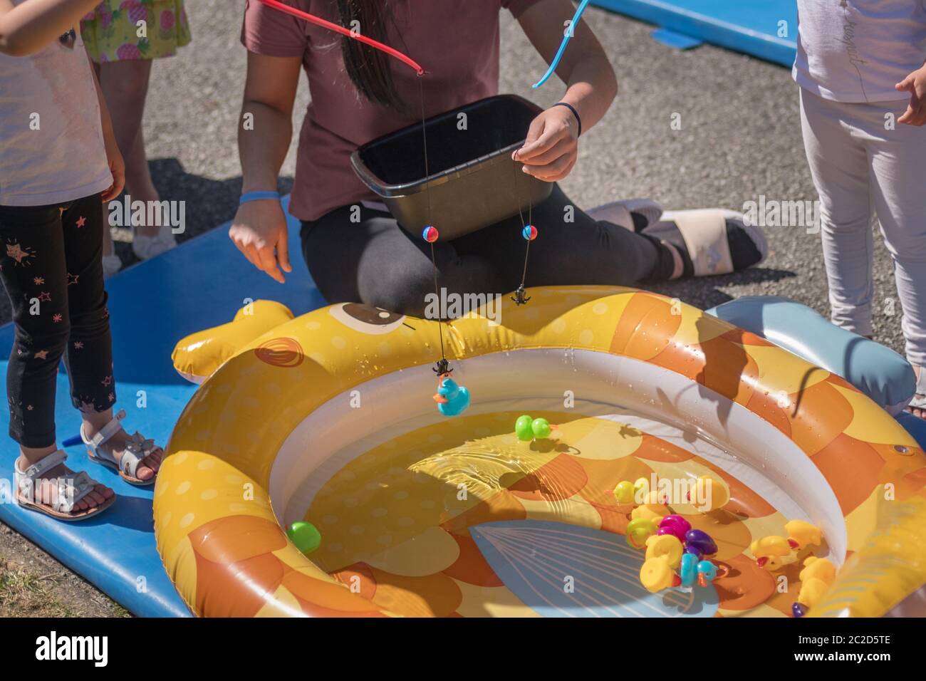Girls catch rubber ducks with fishing rod Stock Photo Alamy