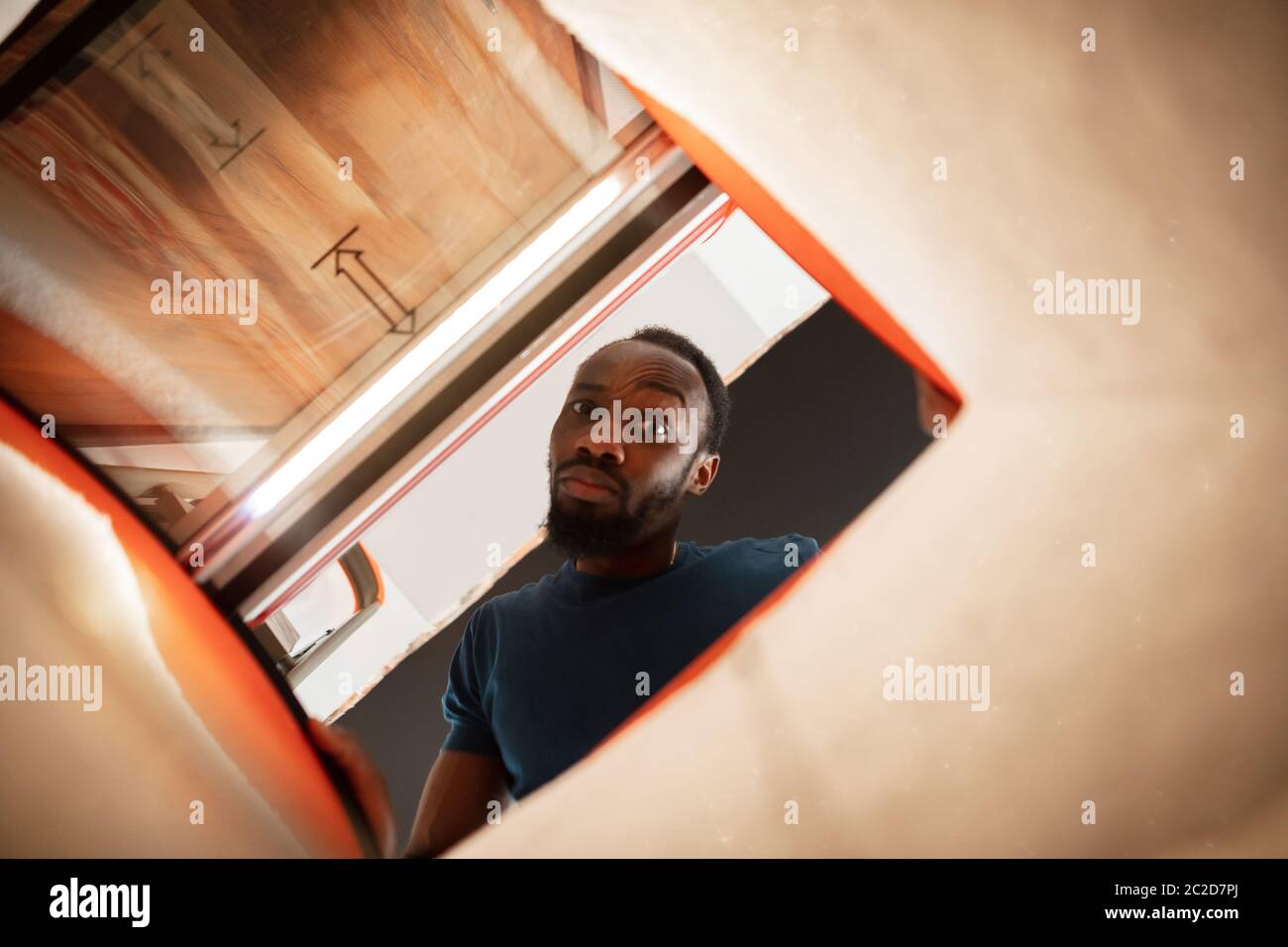 In old postal, delivery box. African-american man looking for job in unusual places at his home. Crazy, funny way to find career and going up. Concept of crisis, unemployment, finance, business. Stock Photo
