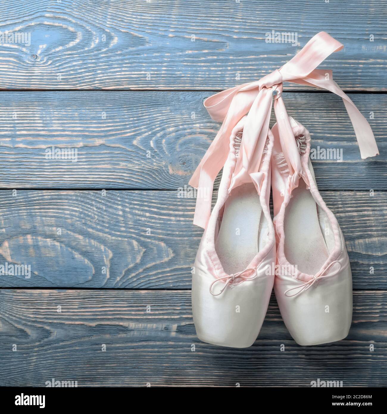 Pointe shoes ballet dance shoes with a bow of ribbons hang on a nail on