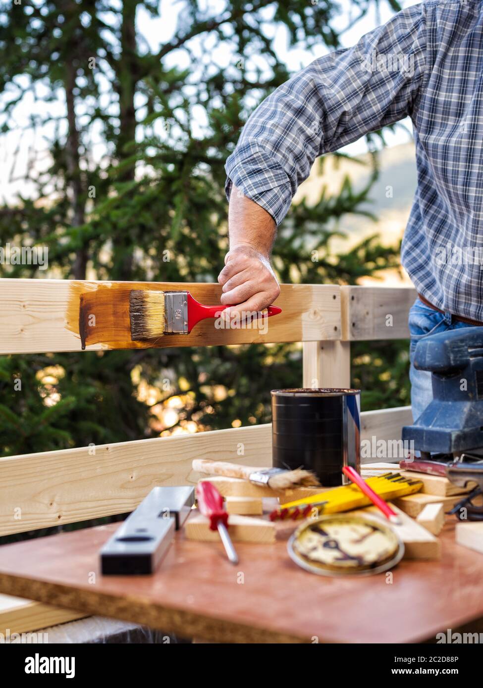 Adult craftsman carpenter with the brush painting the boards of a wooden fence. Housework do it yourself. Stock Photography. Stock Photo