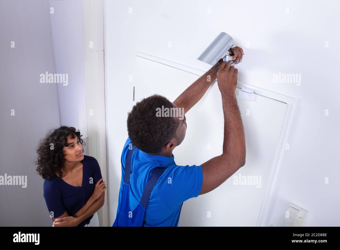 Technician Installing Security Camera System At Home Stock Photo