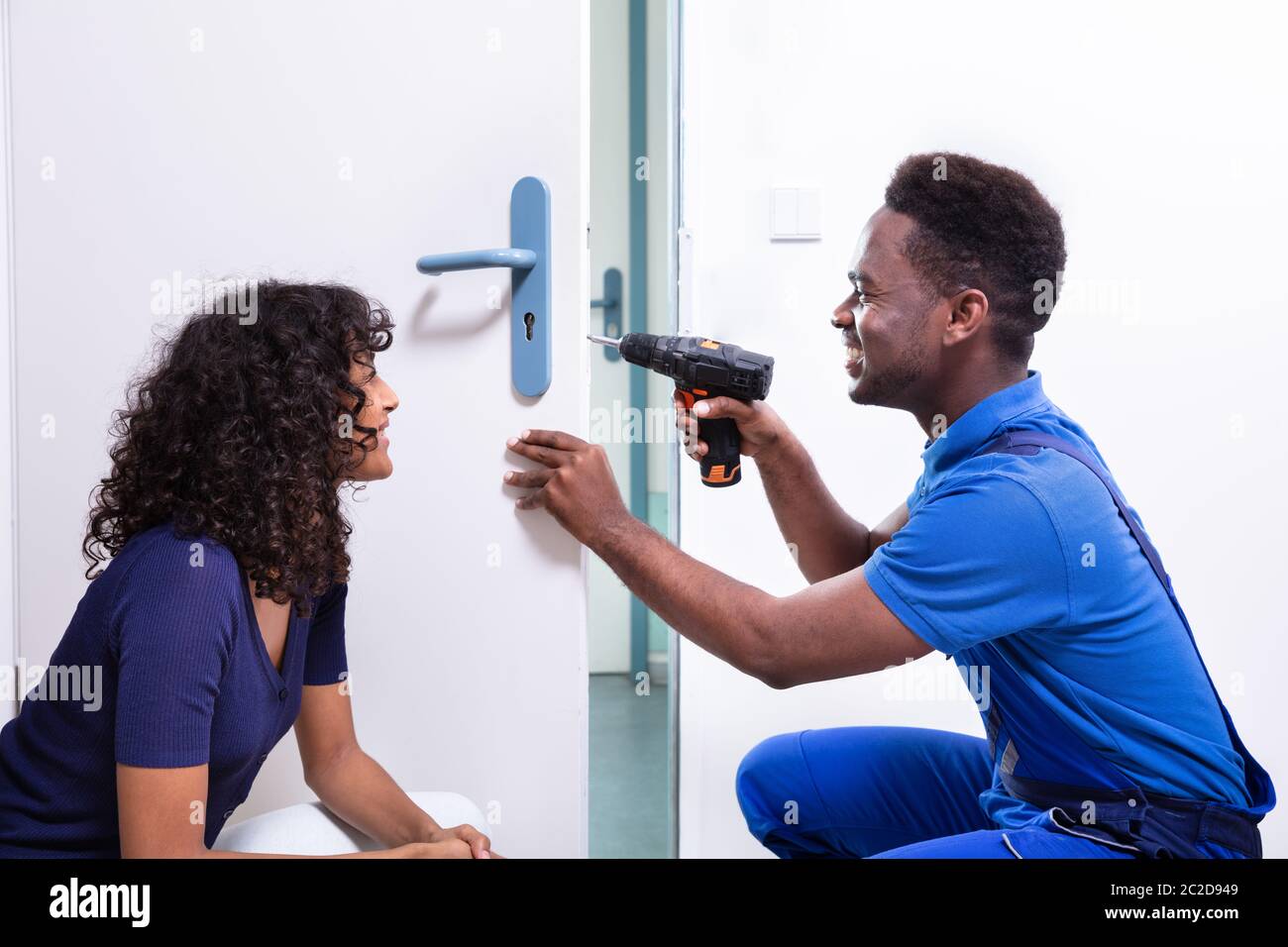 Technician Fixing The Door Lock At Clients Home Stock Photo