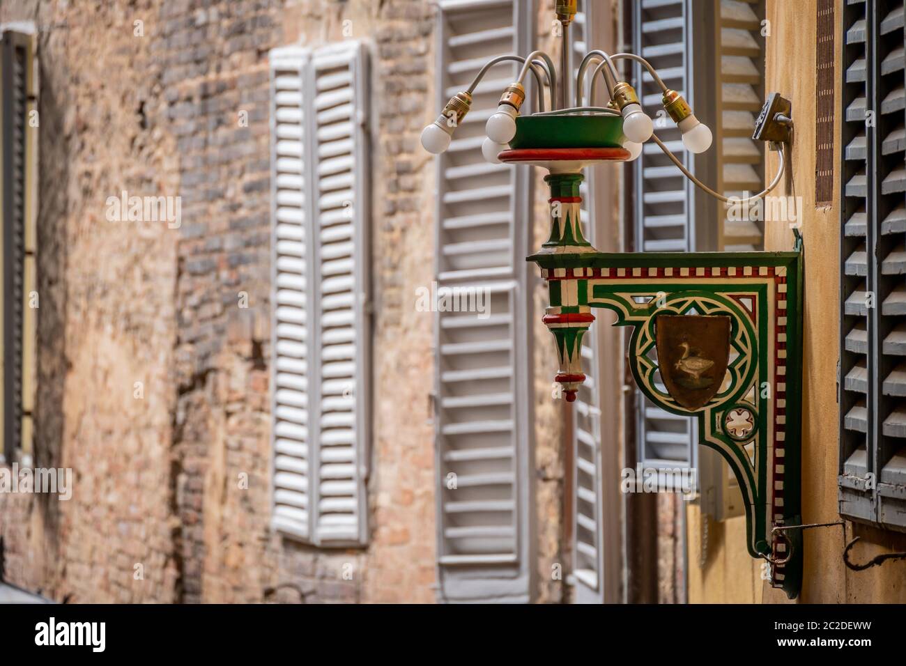 Siena, Italy, April 2018: Street Lamp of the goose district in Siena. Tuscany, Italy. Each colour and shape marks one specific territory which belongs to one specific Contrada. High quality photo Stock Photo