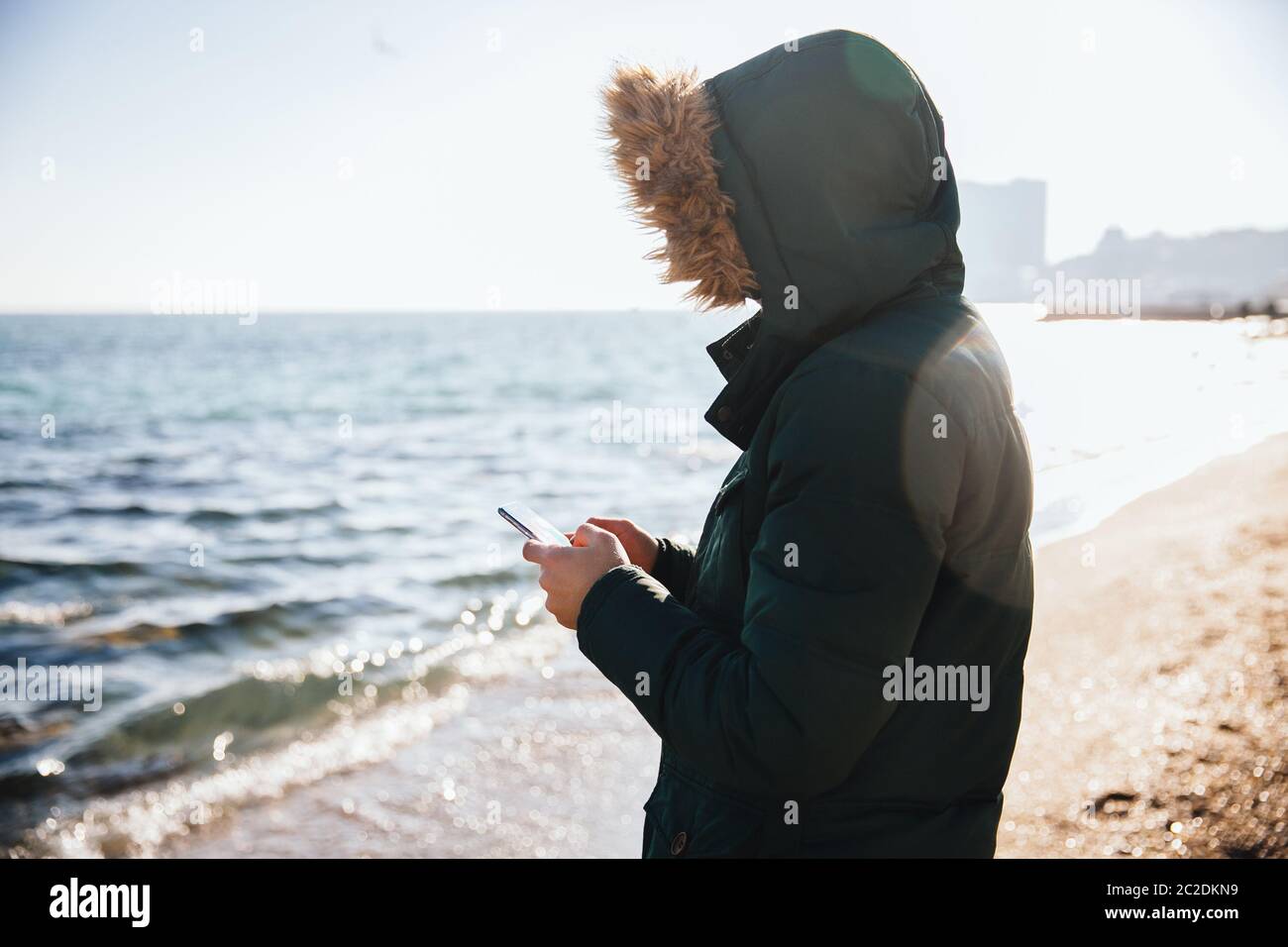 Young man using smartphone while standing by the sea Stock Photo
