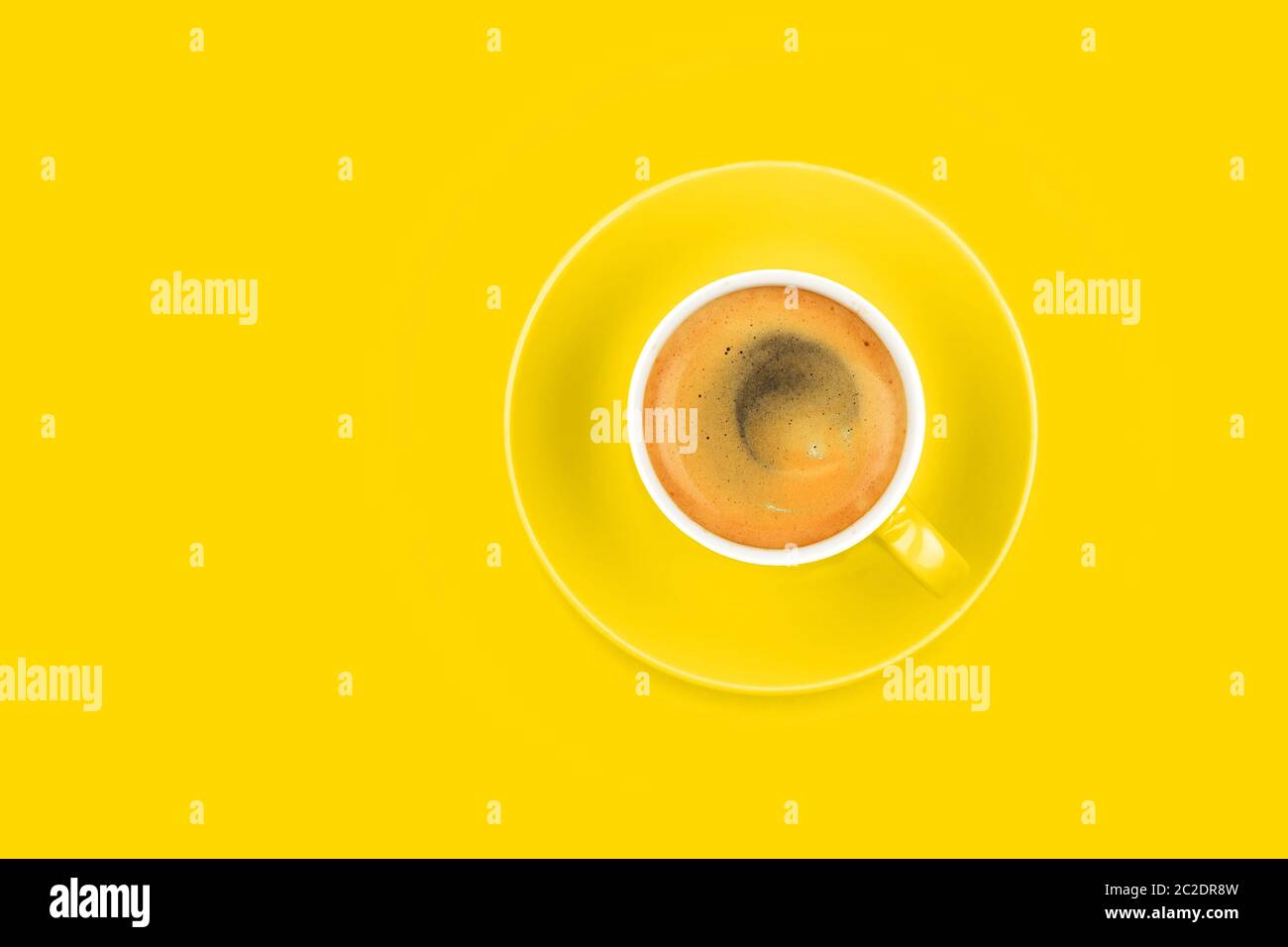 One full espresso coffee cup with saucer over vivid yellow paper ...