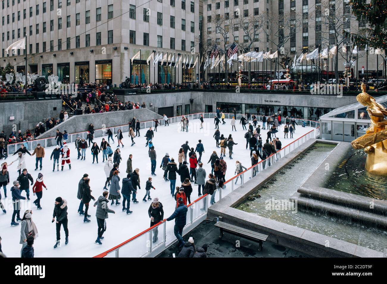 Seasonal ice skating rink with a golden statue, in a famed complex with upscale shops  restaurants in Rockefeller Center  Midtow Stock Photo