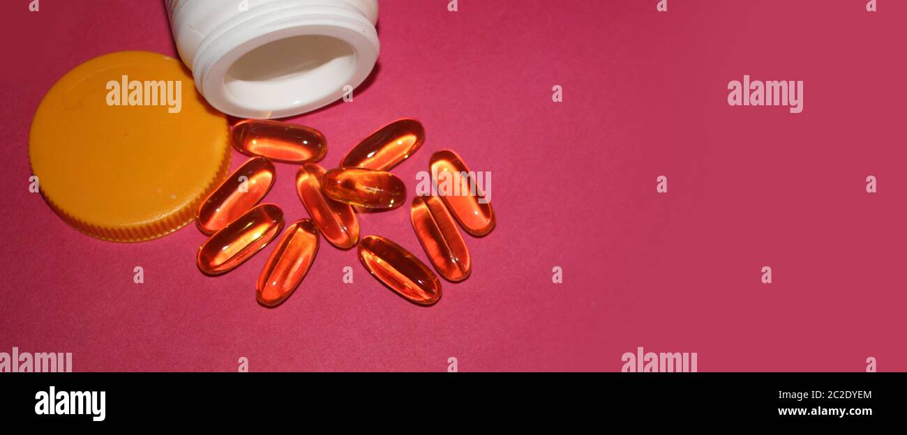 Fish oil Omega-3 capsules and open bottle on rosy red background, wide  banner. Healthcare concept Stock Photo - Alamy
