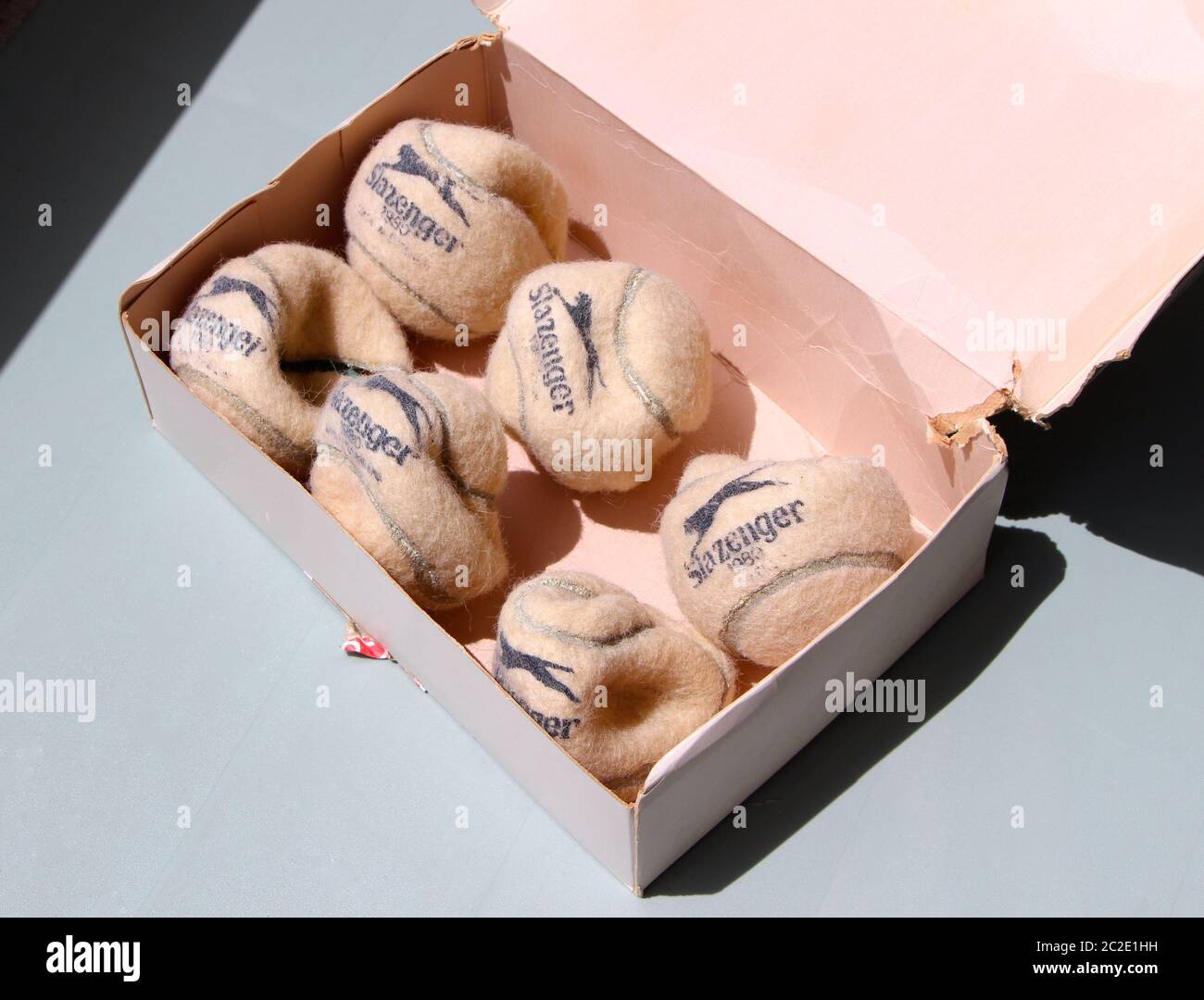Six old destroyed Slazenger tennis balls in a box with the lid open