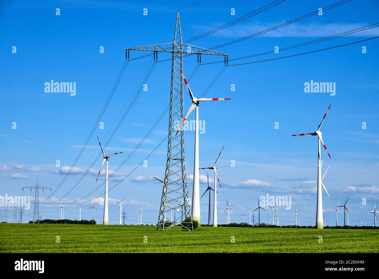Overhead power lines and wind engines on a sunny day seen in Germany Stock Photo